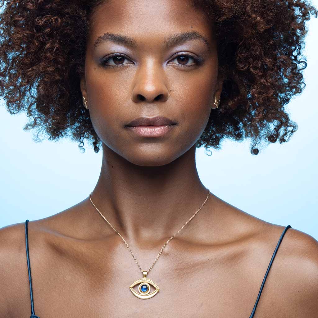 beautiful woman wearing a 14k gold evil eye necklace set with a blue kyanite gemstone handcrafted by Jane Bartel Jewelry