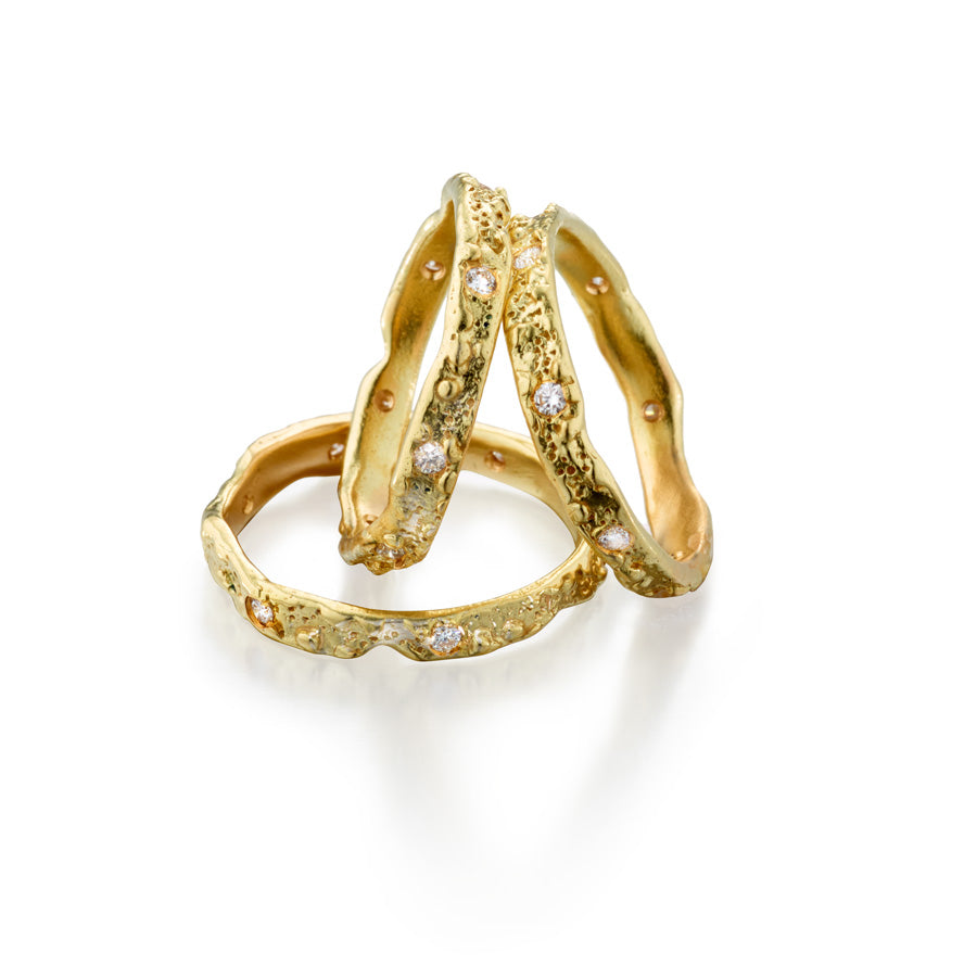 18k gold circle of love gold wedding bands with white diamonds. Delicately textured and inspired by the ocean these alternative wedding bands are crafted using recycled gold and responsibly sourced gemstones in New York City. Ocean Inspired Jewelry.